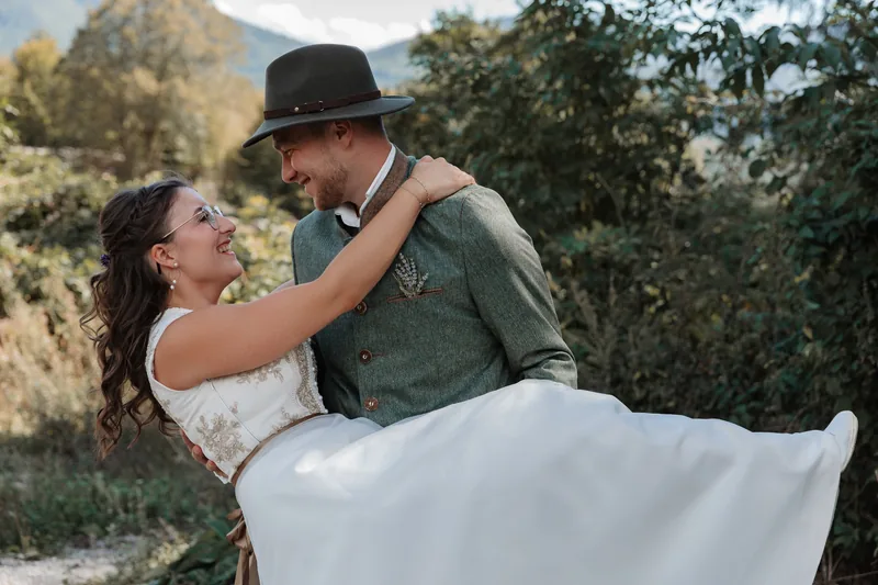 Bräutigam in Tracht trägt seine Braut – Hochzeitsfotografin in Niederösterreich